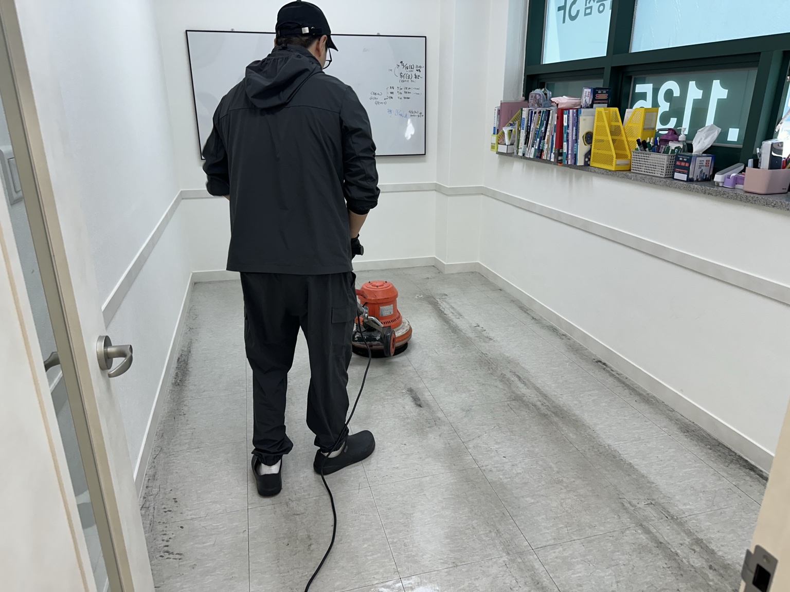 청소요원이 전문 장비로 바닥을 세척하는 실제 현장